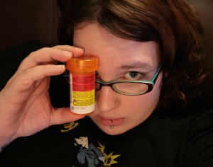 A woman holds up a bottle of pills