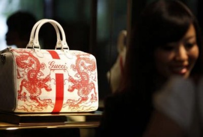 A staff member of the new Gucci flagship store in Shanghai chats with customers next to a bag on display on its opening day